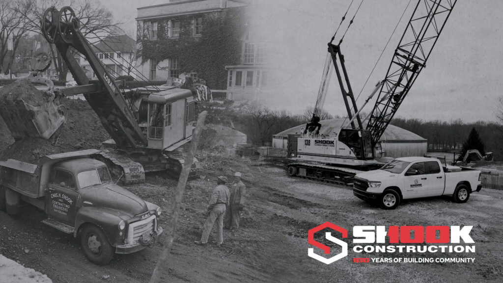 Split black and white image: left side shows vintage construction vehicles and workers; right side shows modern construction equipment and trucks with the Shook Construction logo and 100 Years of Building Community text.