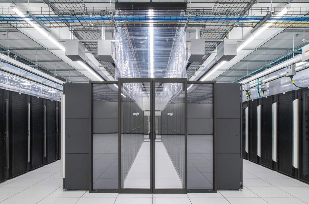 A modern data center with rows of black server racks, bright overhead lighting, and a reflective floor, showing an organized and clean environment for information technology infrastructure.