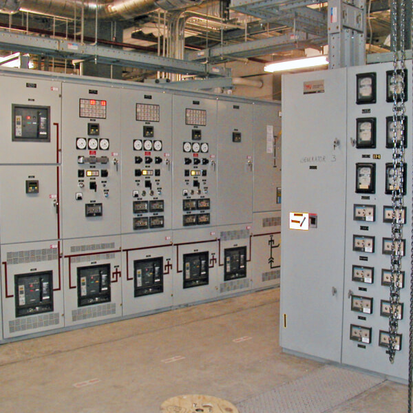 A room with multiple electrical control panels, gauges, switches, and circuit breakers used for managing and monitoring power and electrical systems in an industrial or commercial facility.