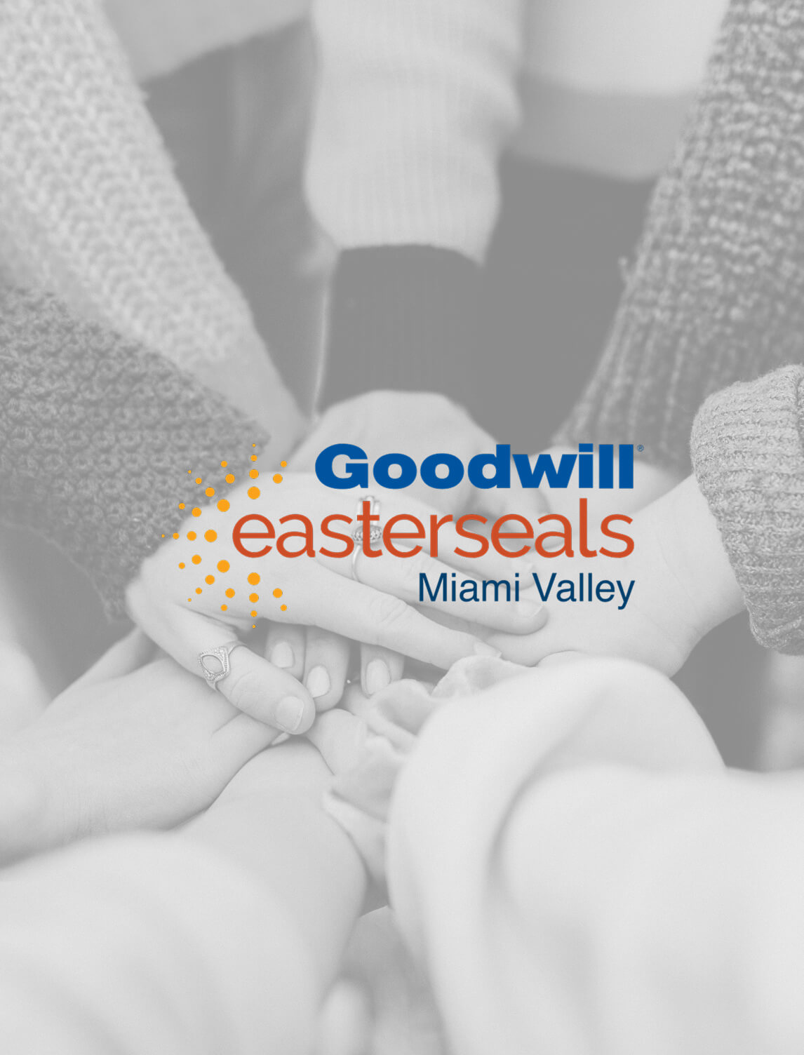 A group of hands joined together in the center, symbolizing unity, with the Goodwill Easterseals Miami Valley logo overlaid on the image.